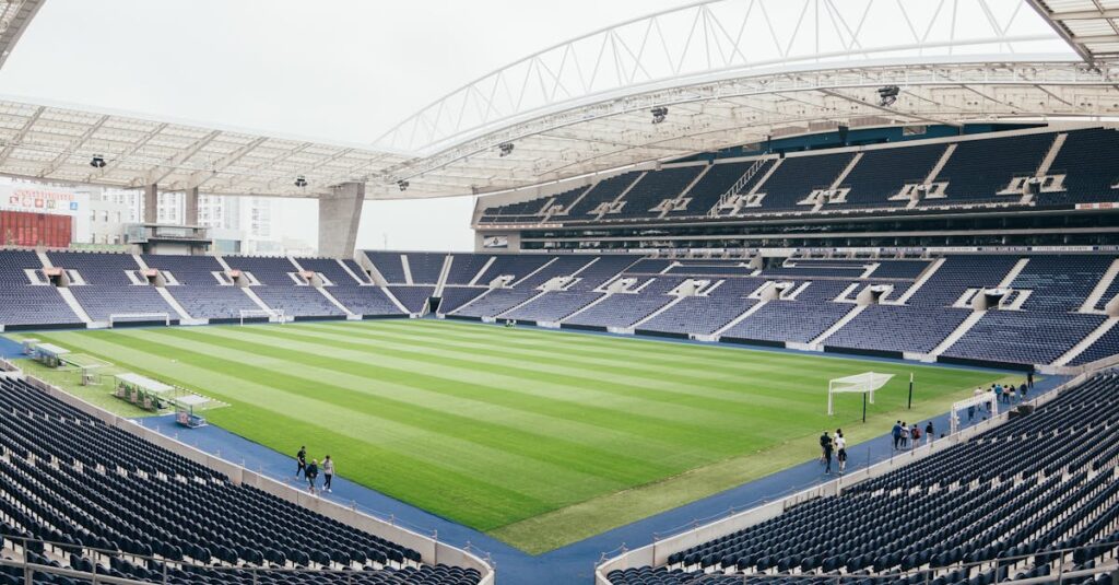 Wide-angle view of a contemporary stadium featuring empty bleachers and a well-maintained grass field, perfect for various sports.