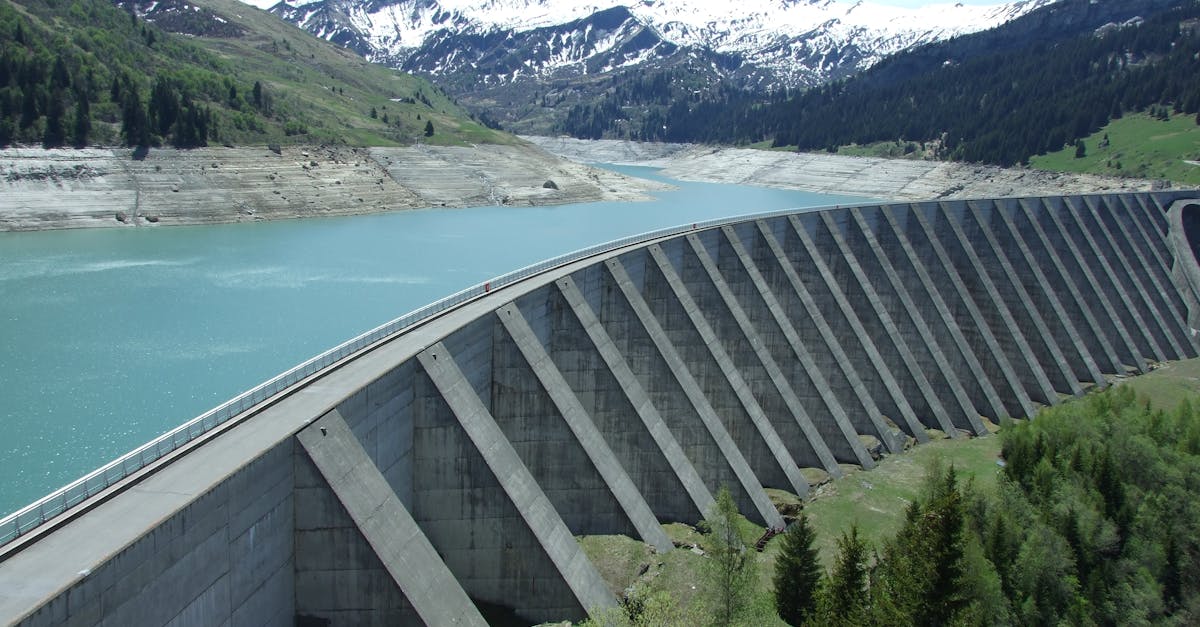 A breathtaking view of a dam amidst a serene alpine landscape with snow-capped mountains.